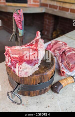 Viande crue sur un pont, un couteau coincé dans la viande. Viande fraîche sur une planche à découper. Gros plan. Banque D'Images