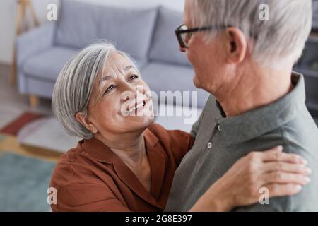 Portrait en grand angle d'un couple senior aimant dansant à la maison ensemble et regardant l'un l'autre avec amour Banque D'Images