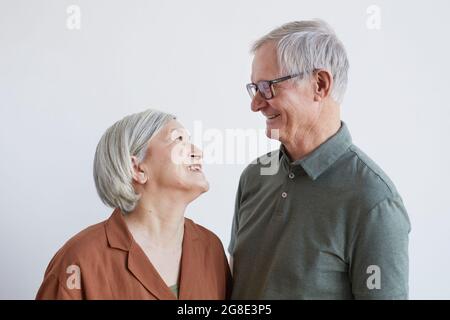 Portrait d'un couple aîné heureux regardant l'un l'autre avec amour tout en se tenant sur fond blanc Banque D'Images