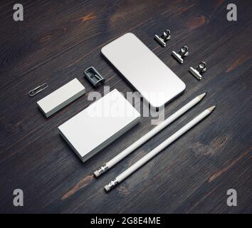 Photo de smartphone vierge, cartes de visite, crayons, gomme et taille-crayon sur fond de table en bois. Maquette de papeterie. Banque D'Images