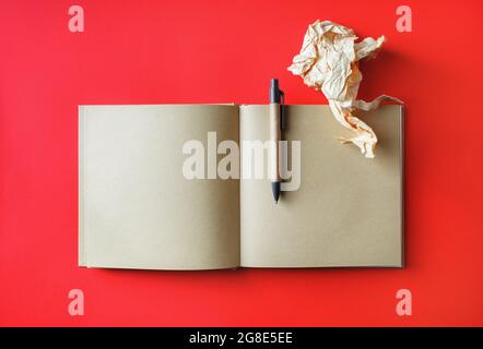 Photo de livre ouvert kraft avec pages vierges, papier froissé et stylo sur fond de papier rouge. Maquette pour placer votre modèle. Vue de dessus. Pose à plat. Banque D'Images
