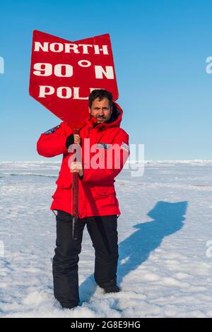Homme posant avec un panneau Pôle Nord sur le Pôle Nord, Arctique Banque D'Images