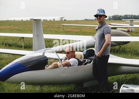 Un club qui s'évolte, prêt pour le vol à bord d'un avion de planeur. Petit sport d'aviation. Deux personnes vérifient le tableau de bord de l'habitacle d'un avion d'époque Banque D'Images