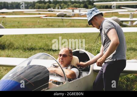 Un club qui s'évolte, prêt pour le vol à bord d'un avion de planeur. Petit sport d'aviation. Deux personnes vérifient le tableau de bord de l'habitacle d'un avion d'époque Banque D'Images