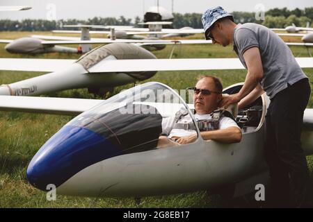 Un club qui s'évolte, prêt pour le vol à bord d'un avion de planeur. Petit sport d'aviation. Deux personnes vérifient le tableau de bord de l'habitacle d'un avion d'époque Banque D'Images