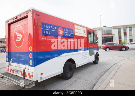 Un camion de livraison de postes Canada conduit et s'approche de la voie du service de livraison du courrier. Banque D'Images
