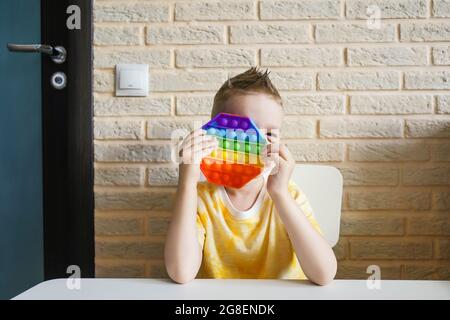 Garçon jouant avec le silicone coloré antistress pop il jouet. Banque D'Images