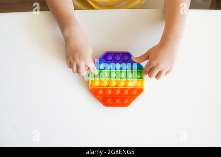 Mettez le violon dans les mains des enfants. Jouet coloré pousser le pop. Vue de dessus du violon sensoriel antistress. Banque D'Images