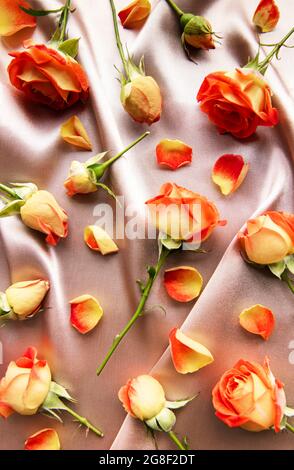 Composition des fleurs. Cadre fait de roses rouges et de feuilles sur fond de soie. Vue de dessus, plat, espace de copie Banque D'Images