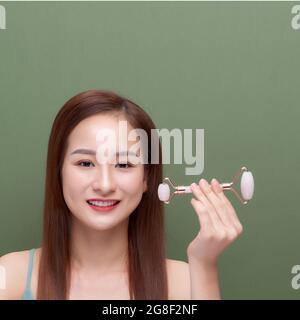 Photo portrait d'une jeune femme qui a l'air d'une utilisation détendue tout en utilisant un rouleau à cadran en quartz rose naturel Banque D'Images