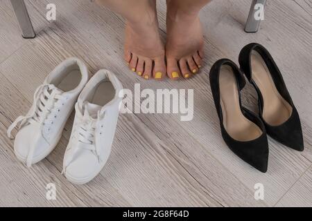 Une femme choisit entre des baskets confortables et des chaussures de bureau. Vue de dessus Banque D'Images