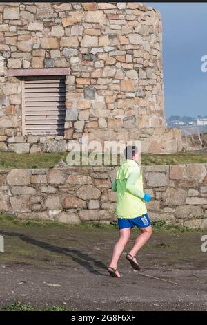 Un coureur qui fait un jogging devant une tour en pierre sur Towan Head à Newquay, en Cornouailles. Banque D'Images