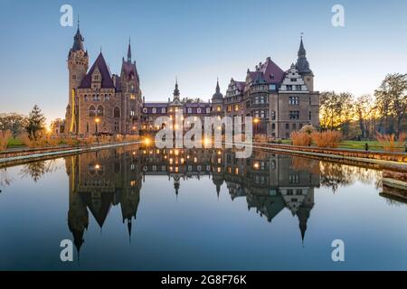 Vue sur le château de Moszna (Moszna Zamek) qui se reflète dans l'eau au crépuscule, Opole Voivodeship, Pologne Banque D'Images
