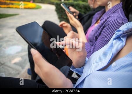 Les femmes utilisent leur téléphone intelligent à l'extérieur du parc. Banque D'Images