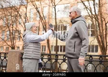 Portrait de vue latérale d'un couple senior actif de haut cinq à l'extérieur et souriant heureux Banque D'Images