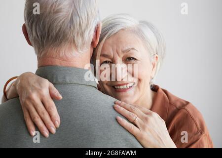 Portrait d'une femme âgée heureuse, épousant son mari et regardant l'appareil photo sur fond blanc Banque D'Images