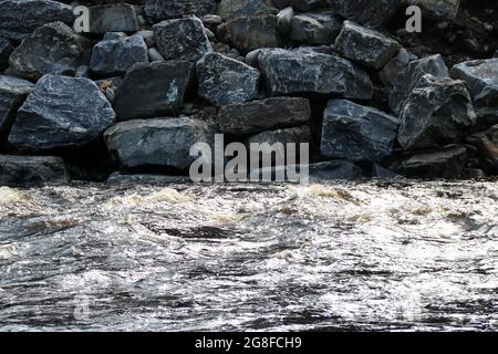 Rivière rapide avec rive de rivière parsemée de rochers Banque D'Images