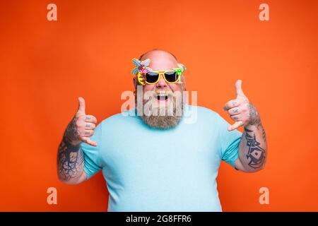 Gros Happy man avec barbe, tatouages et lunettes de soleil est prêt pour l'été Banque D'Images