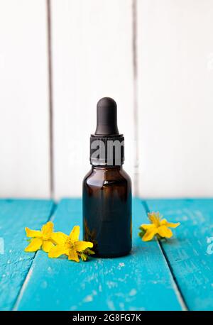 Hypericum perforatum connu sous le nom de teinture de millepertuis ou bouteille d'huile avec fleurs végétales pour la décoration sur fond de bois blanc. Banque D'Images