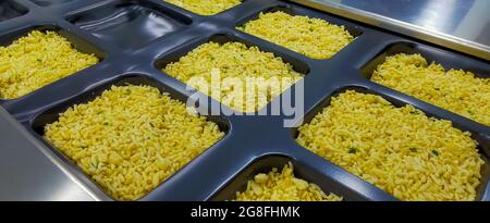 Riz frit congelé avec œuf dans un plateau en plastique, en attente de l'étiquette d'étanchéité supérieure avec thermoformage dans l'usine alimentaire. Industrie des aliments surgelés. Repas prêt Banque D'Images