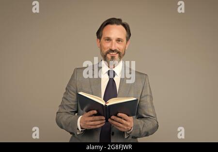 Happy School enseignant en costume formel tenir livre ouvert enseignement leçon fond gris, littérature Banque D'Images