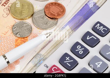 Billets et pièces en livres sterling avec un stylo et une calculatrice. Banque D'Images