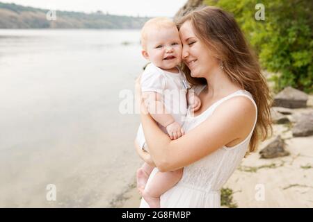 Mère avec bébé à l'extérieur près de la rivière. Le concept d'une famille heureuse Banque D'Images