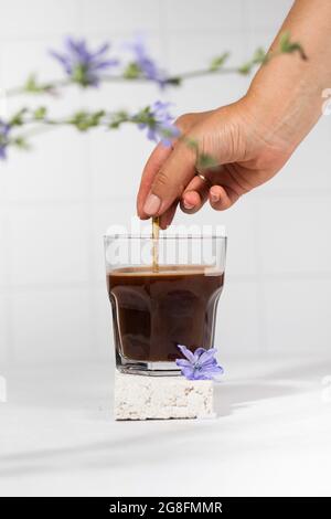 Boisson à la chicorée dans une tasse transparente avec fleurs à la chicorée au premier plan. Banque D'Images