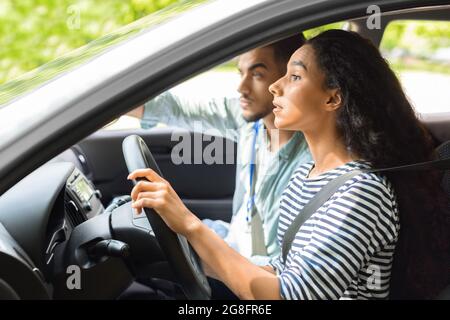 Une jeune femme nerveuse qui conduit un étudiant au volant d'une voiture avec un instructeur Banque D'Images