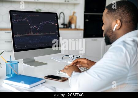 Investissements, négociation sur la bourse. African american MAN Trader investisseur, analyse le marché financier de crypto-monnaie, regarde l'ordinateur, le graphique d'index de données de trading sur l'écran de pc Banque D'Images