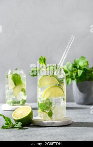 Cocktails mojito frais de rhum blanc, soda, citron vert et menthe sur fond gris. Verticale. Gros plan. Banque D'Images
