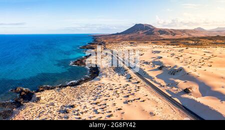 Route vide traversant les dunes de sable surplombant l'océan, Parc naturel de Corralejo, Fuerteventura, Iles Canaries, Espagne, Atlantique, Europe Banque D'Images