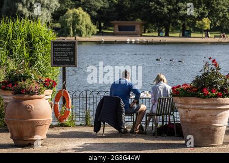 Un couple prend un petit déjeuner décontracté avec vue sur le lac de Serpentine à Hyde Park, dans le centre de Londres, en Angleterre, au Royaume-Uni Banque D'Images