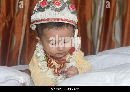 Bébé garçon souriant et assis sur le lit dans une tenue de mariage bengali traditionnelle. Portrait en gros plan mignon Sweet Little Infant. Ethnie indienne. Enfant Banque D'Images