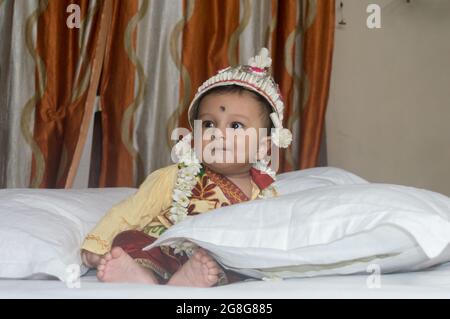 Bébé garçon souriant et assis sur le lit dans une tenue de mariage bengali traditionnelle. Portrait en gros plan mignon Sweet Little Infant. Ethnie indienne. Enfant Banque D'Images