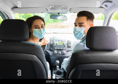 Mari et femme dans les masques protecteurs de visage de conduite automobile Banque D'Images