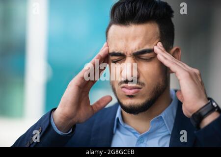 Un jeune homme d'affaires arabe stressé souffrant de maux de tête Banque D'Images