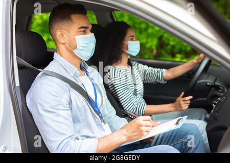 Instructeur de conduite et femme brune assise à l'intérieur de la voiture Banque D'Images