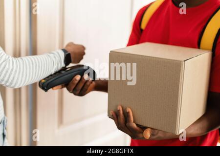 Lady paying Courier pour la livraison de colis en utilisant Smartwatch intérieur, Cropped Banque D'Images