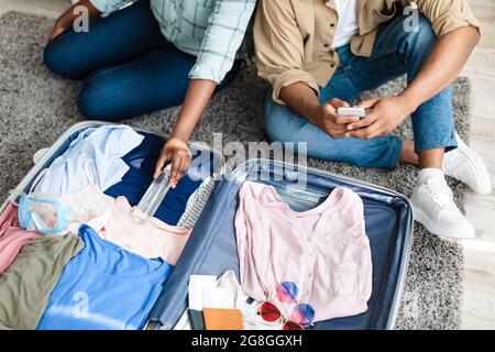 Black touristes couple mettre Sanitizer emballage voyage Suitcase à la maison Banque D'Images