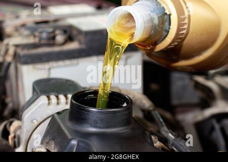 Le maître d'entretien de la voiture verse de l'huile moteur pour le moteur de la voiture. Entretien de la voiture, propreté du moteur, station-service de voiture. Banque D'Images