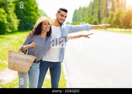 Couple multiracial Hitchiking, arrêtant la voiture sur la route Banque D'Images