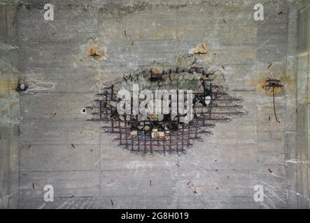 Fissure dans une fissure massive de béton. Quelque chose a explosé de l'autre côté de cette barre d'armature en béton rouillé Banque D'Images