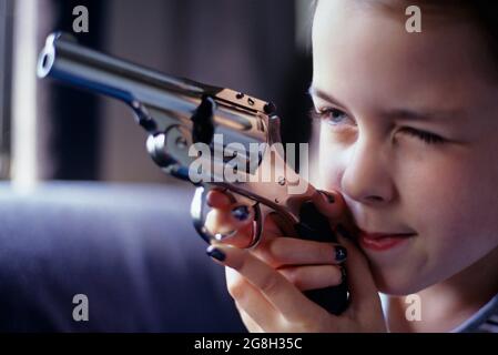 Une jeune fille (8 ans) découvre une arme de poing dans le placard de la chambre des parents tout en snooping pour les bijoux jouant avec une arme à feu Banque D'Images