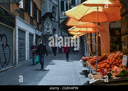 Épicerie avec fruits frais dans la via San Pietro della Porta Alley dans le centre historique de Gênes avec des personnes portant des masques Covid en été, Ligurie Banque D'Images