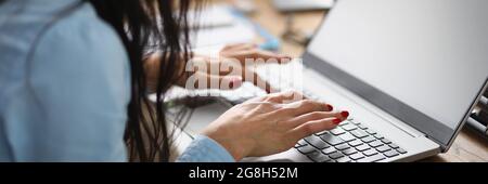 Femme assise à la table et travaillant à un ordinateur portable Banque D'Images