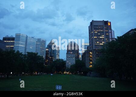 Montréal, QC, Canada - 7-15-2021: Une ligne d'horizon du centre-ville, rue Sherbrooke à l'heure bleue du crépuscule. Le premier plan est le champ inférieur de l'université McGill Banque D'Images