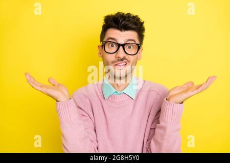 Photo de jeunes mécontents mécontent incertain incertain homme dans des lunettes hausser les épaules isolées sur fond jaune Banque D'Images