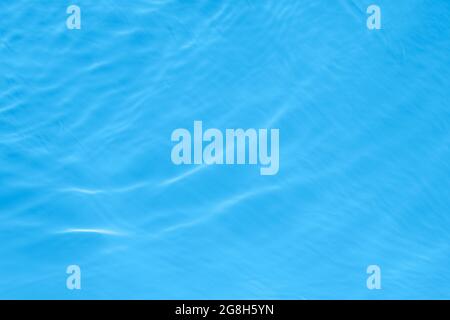 Surface de lumière sur l'eau bleue transparente de la piscine. Arrière-plan ondulé abstrait tendance. Vagues d'eau sous la lumière du soleil. Bannière avec espace de copie. Banque D'Images
