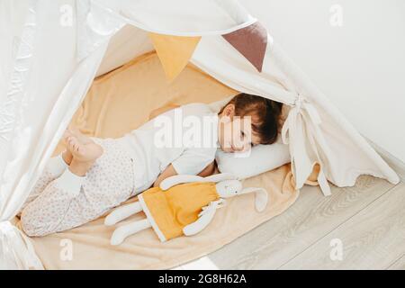 jolie fille jouant dans le tipi avec le tissu tilda lapin à la maison Banque D'Images